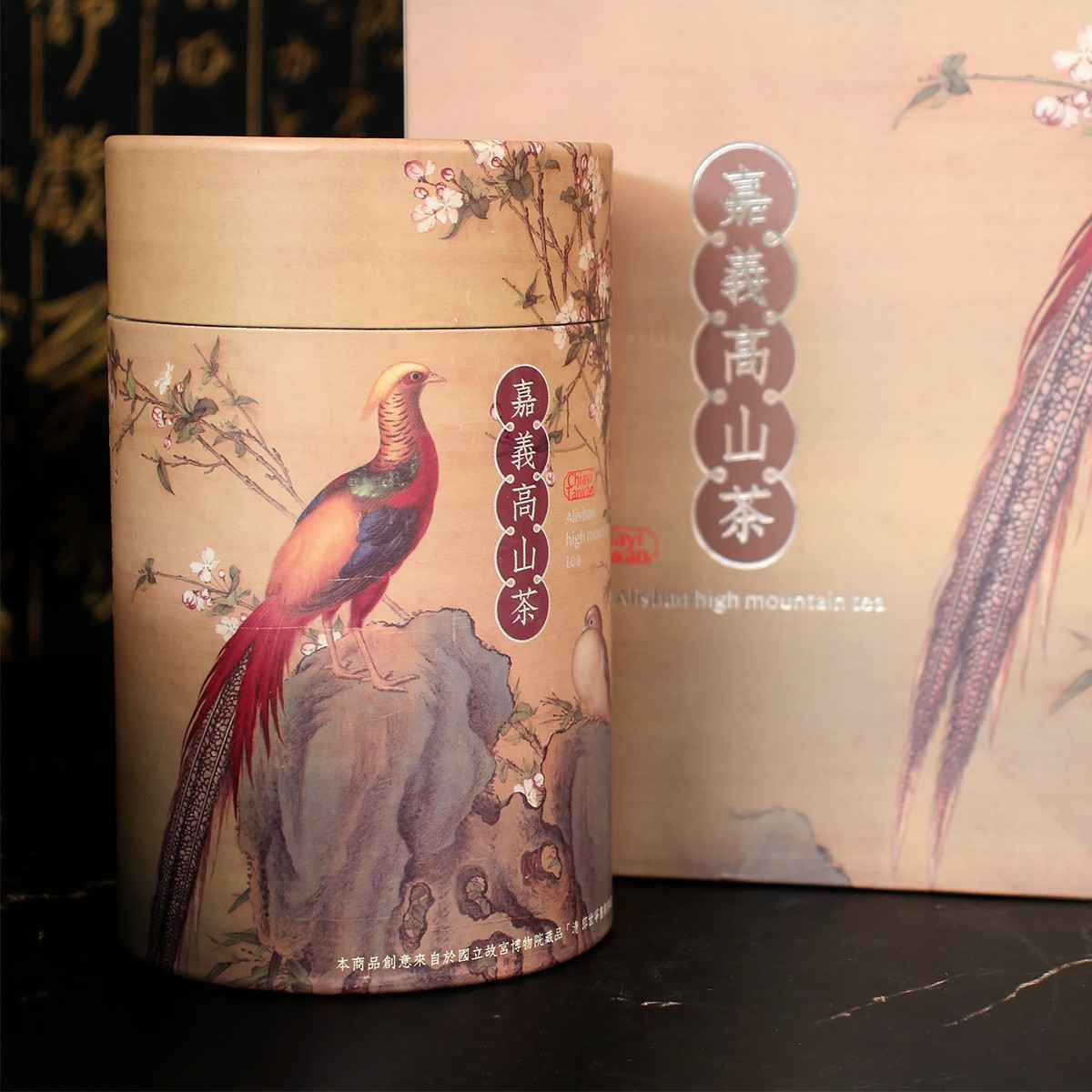 本產品創意來自於國立故宮博物院院藏品「錦春圖」。<br /><br />以郎世寧的「錦春圖」啟發，將其中石上錦雞的形象巧妙地融入了茶葉包裝設計中，象徵著美好的前程，象徵著一片充滿希望與繁榮的未來。並且特別注重了「雞」與「吉」之諧音，寓意著吉祥和好運。結合這些元素來做設計包裝，取「前程似錦」的美好寓意。<br />為了更貼近嘉義的自然環境特色，以嘉義阿里山的春景色為靈感發想，推出了兩款獨特的包裝——「里山青」和「錦櫻紅」。<br />「里山青」是對阿里山春天綠意盎然景象的致敬。包裝上以清新的綠色為主調，展現出一片茂盛的山林和茶園。它代表著大自然的活力和生機，讓品茗的同時感受到大自然的靈感。<br />而「錦櫻紅」則是對嘉義春季櫻花綻放景象的呈現